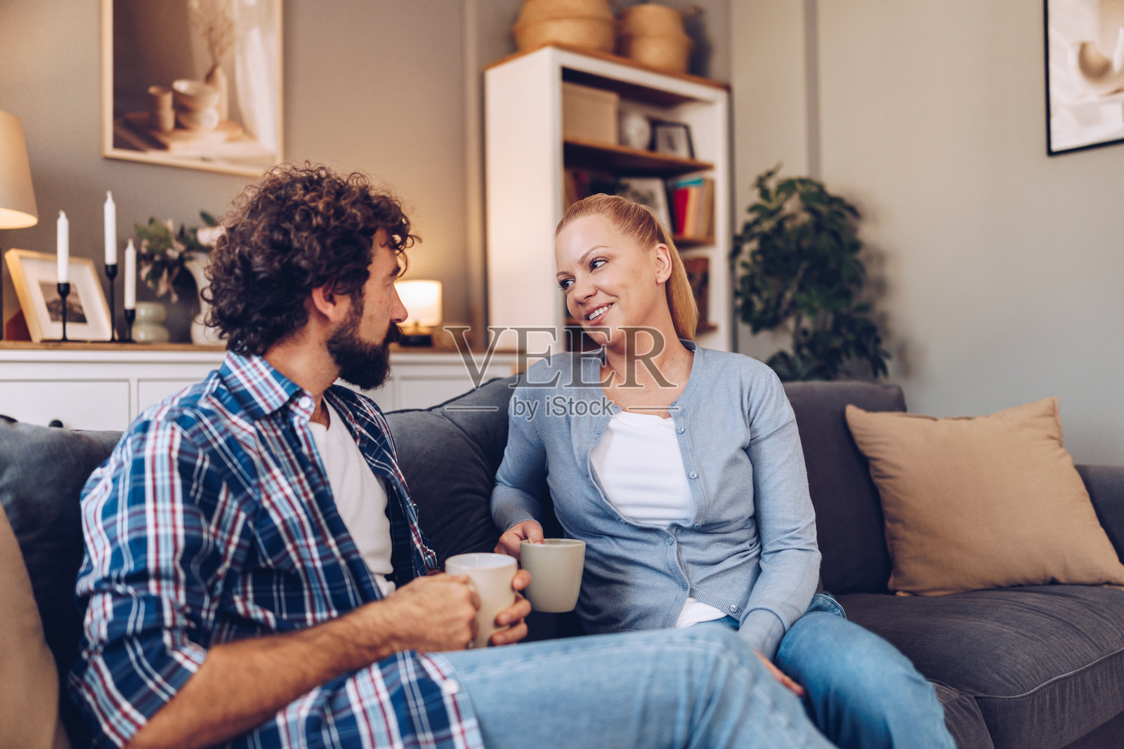 丈夫坐在家里的沙发上谈论问题，妻子正在客厅的沙发上仔细倾听。照片摄影图片