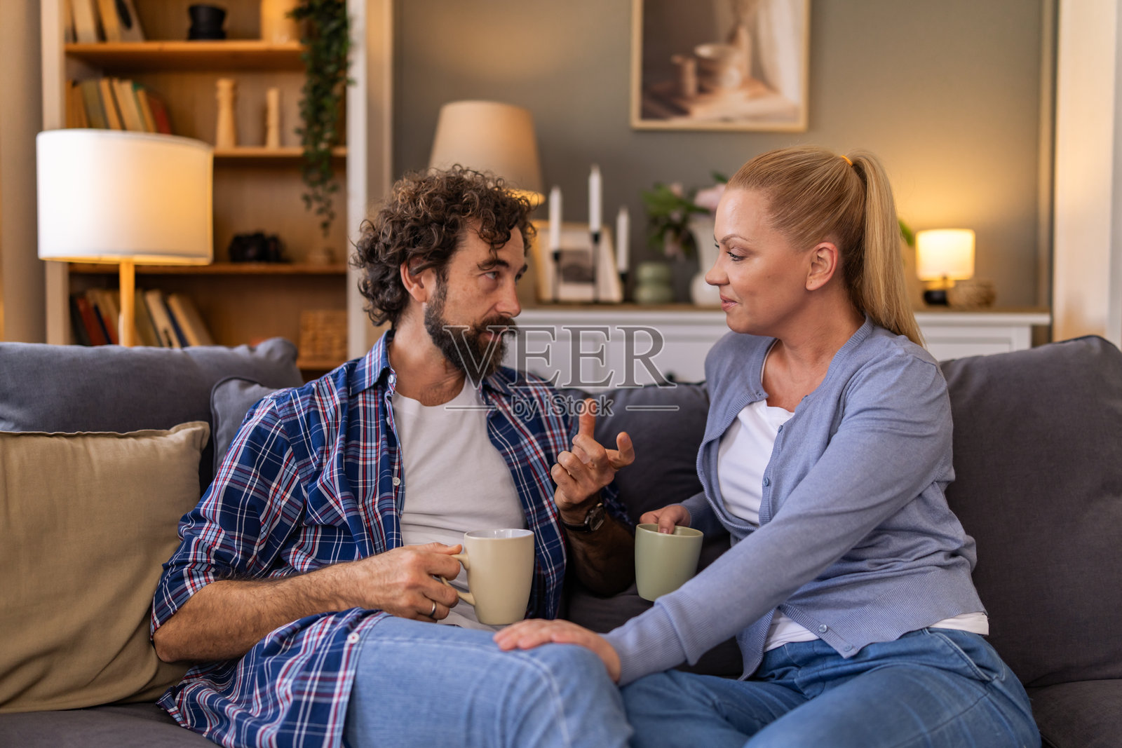 丈夫坐在家里的沙发上谈论问题，妻子认真倾听并支持他，两人一同坐在客厅的沙发上。照片摄影图片