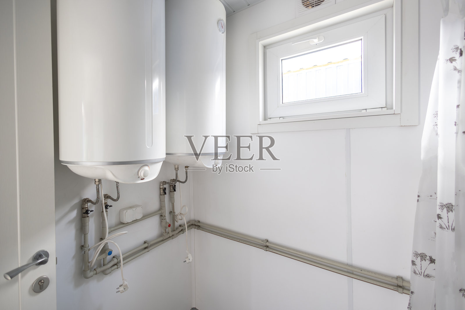 功能性房间或浴室的墙壁上安装了两个大型电热水器，这种设置可确保为工人宿舍等共享设施提供充足的热水。照片摄影图片