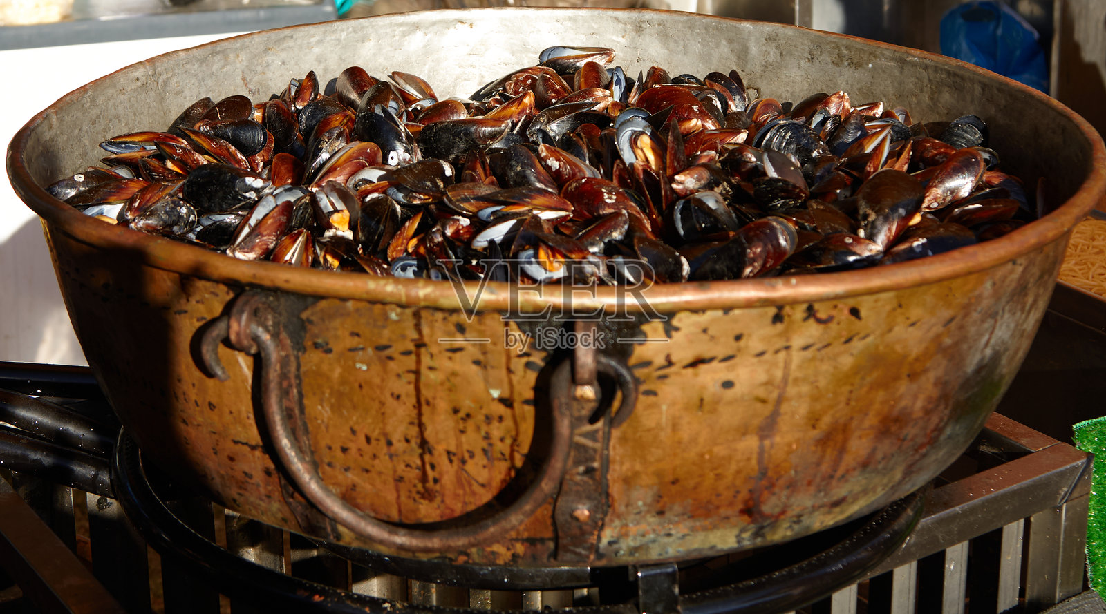 一个大金属碗里装满了新鲜贻贝，展示着它们光泽的外壳和鲜艳的色彩，放在质朴的表面上，突出了海鲜的准备过程和烹饪艺术。照片摄影图片