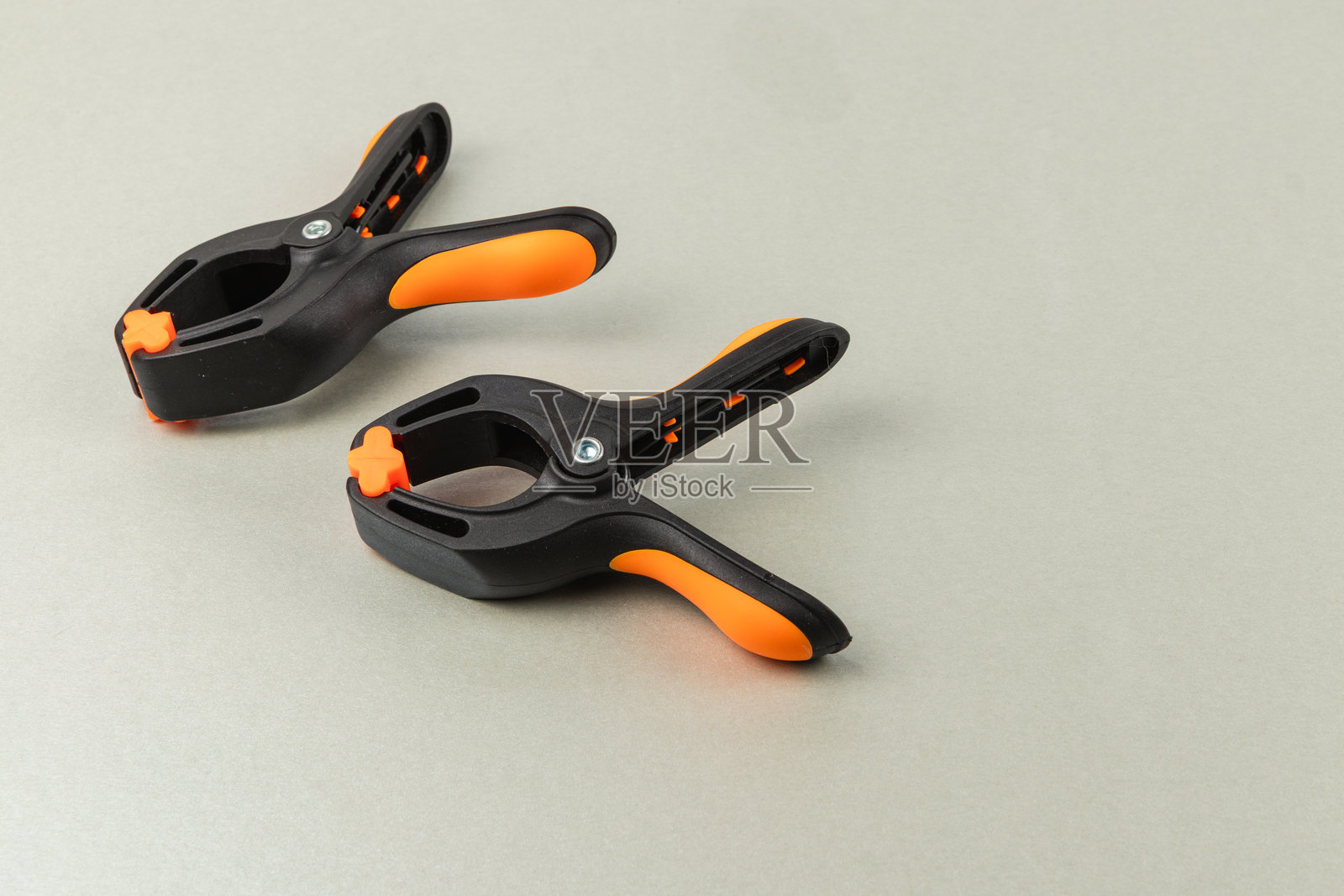 带有橙色手柄的夹子，放置在光滑的表面上，用于手工项目照片摄影图片