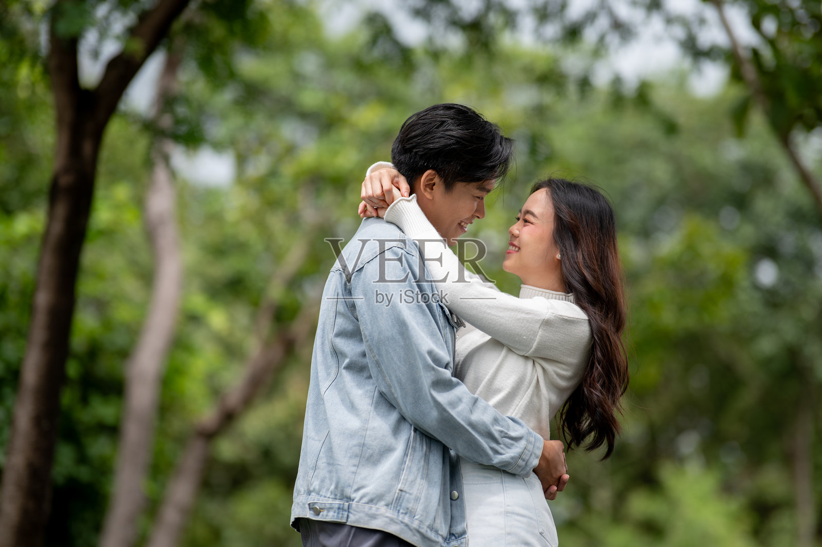 年轻的亚裔情侣，一男一女，在公园户外拥抱在一起。照片摄影图片