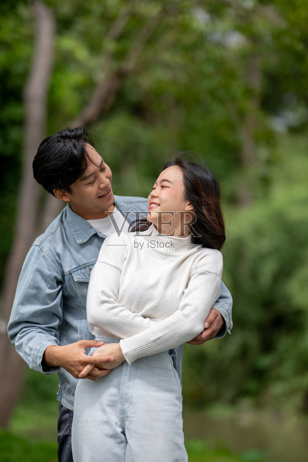 年轻的亚洲情侣在公园户外跳舞，男人牵着手拥抱着女人。照片摄影图片