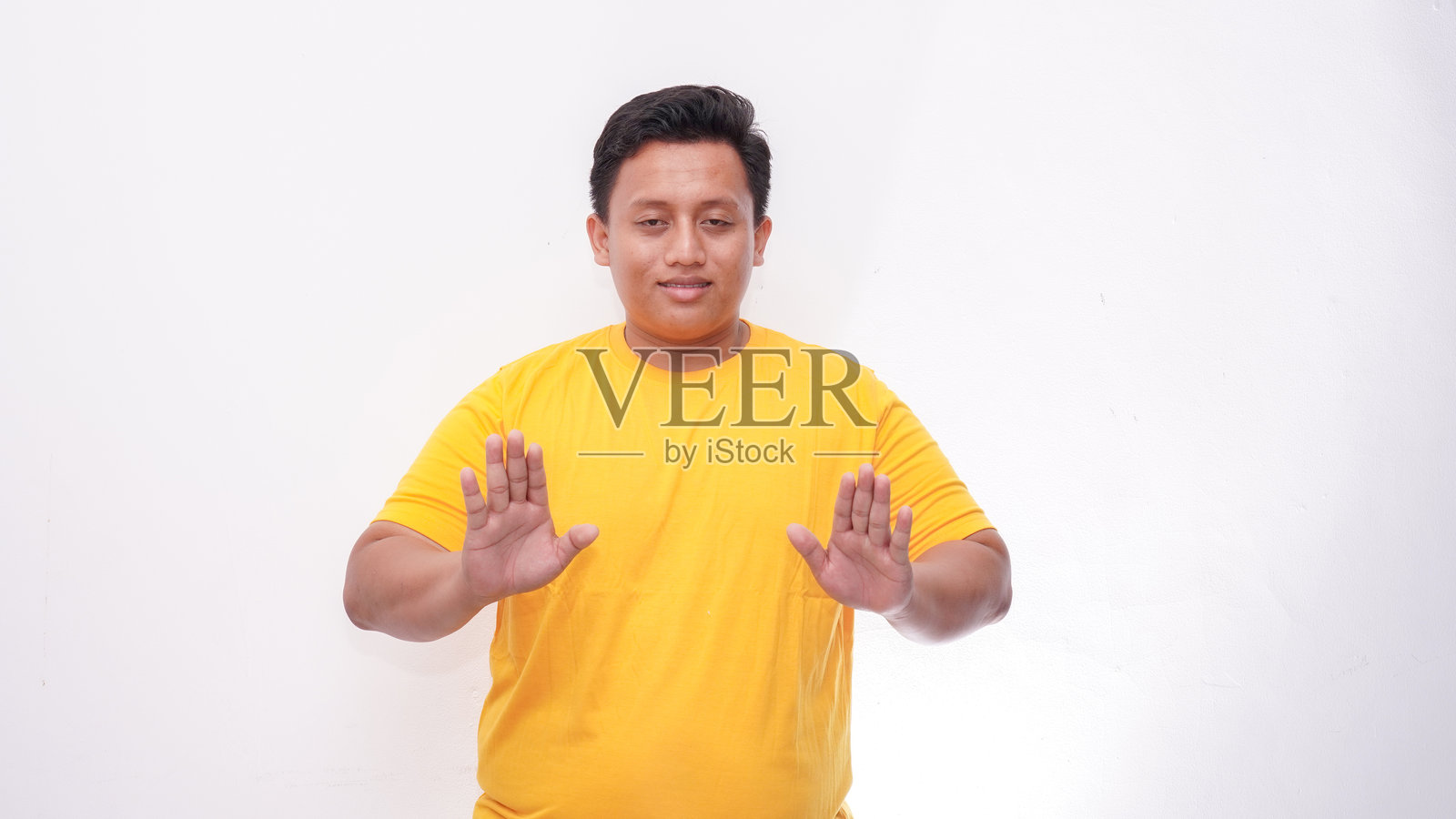 年轻的亚洲胖男人在孤立的背景上打手语照片摄影图片