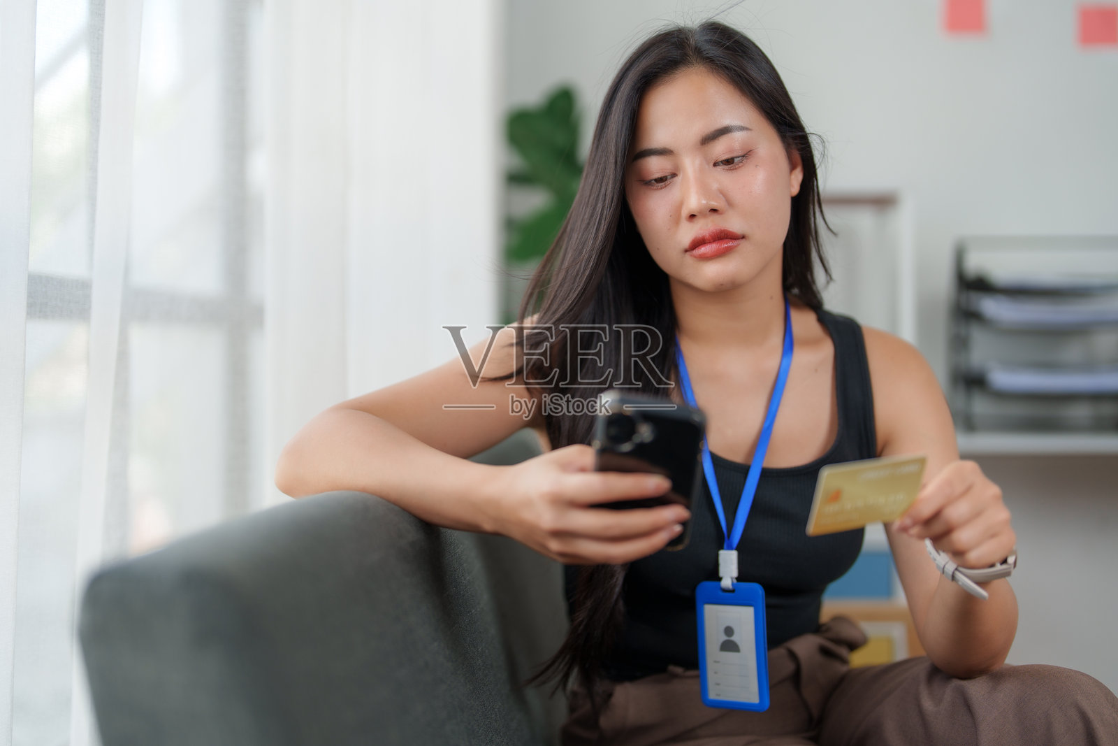 年轻的亚洲女性在家中使用智能手机和信用卡进行在线支付照片摄影图片