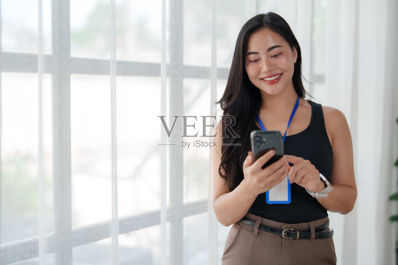 年轻的亚洲女商人在窗边使用智能手机照片摄影图片