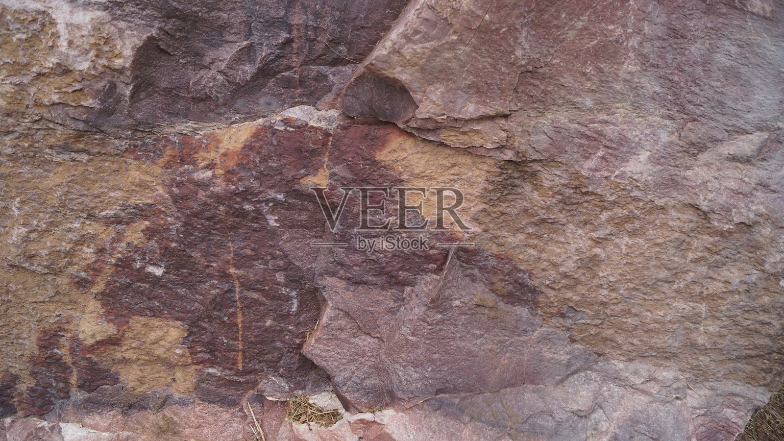 带有深色条纹和苔藓的红褐色岩石照片摄影图片