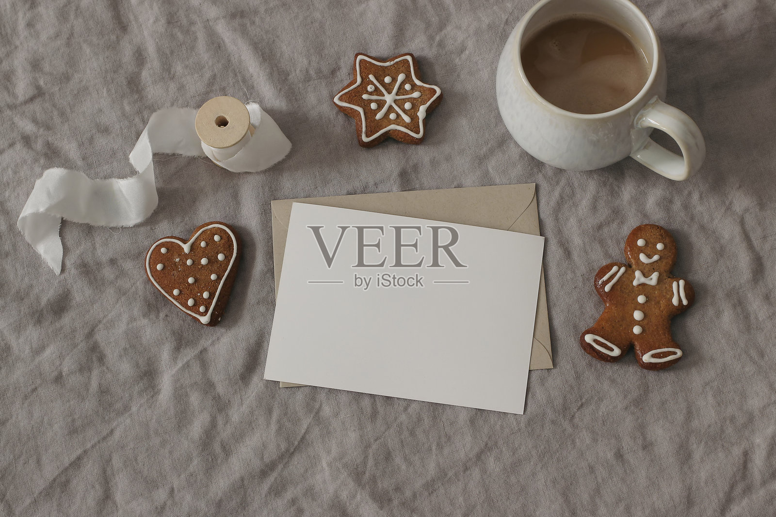 圣诞节文具。空贺卡特写，邀请函模型。一杯咖啡，白色南瓜。亚麻桌布。带糖霜装饰的姜饼。冬季假日俯视平铺。照片摄影图片