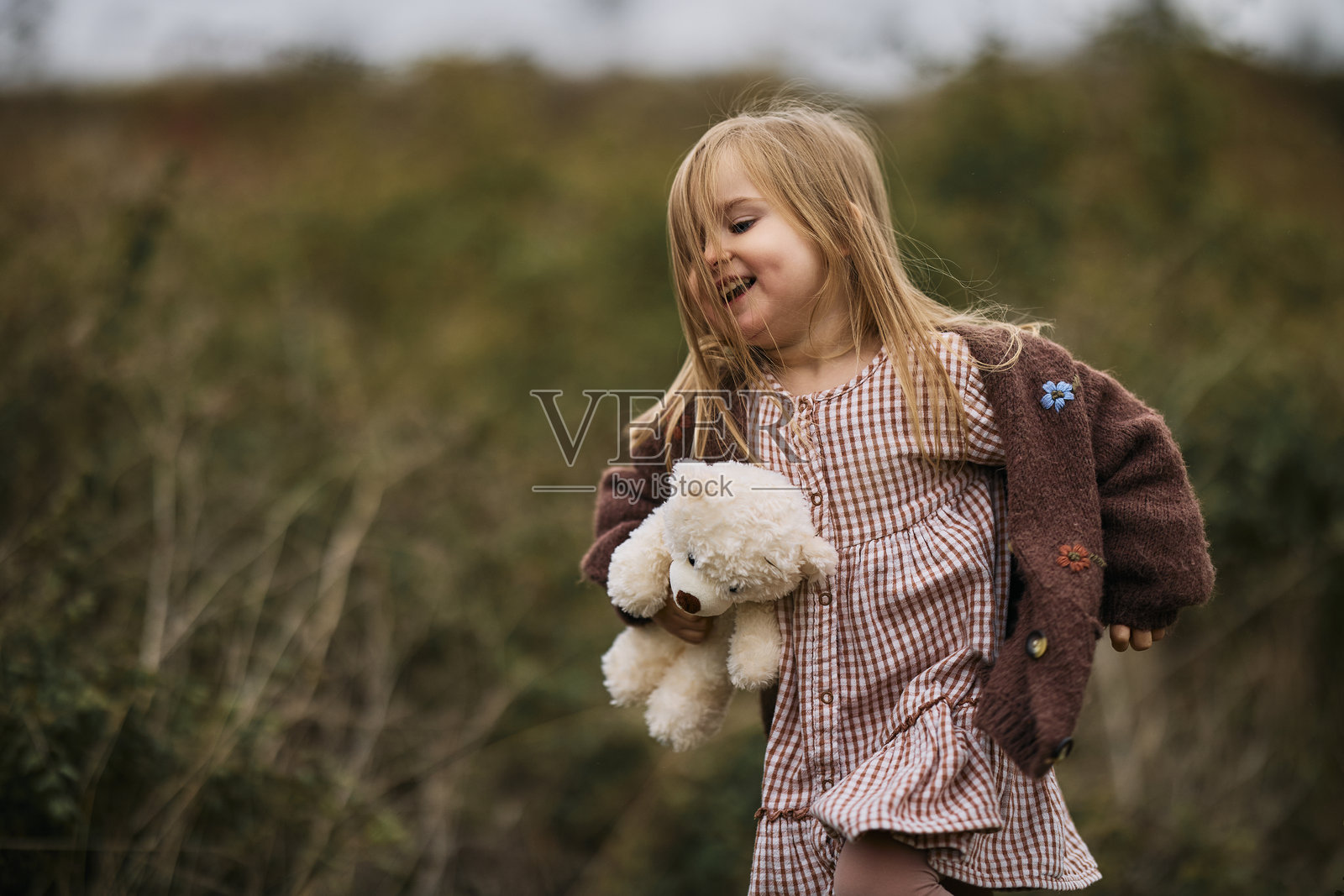 快乐的孩子在户外奔跑，手里拿着泰迪熊照片摄影图片