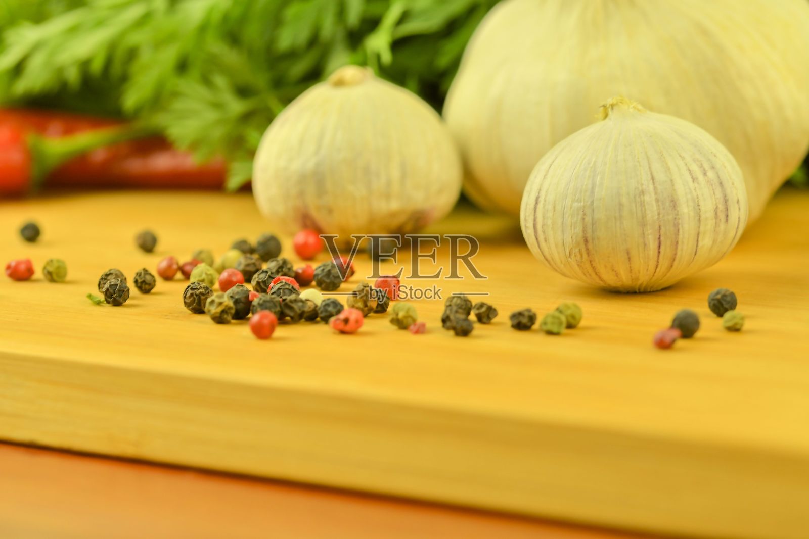 木质砧板上放着大蒜、红辣椒、四色彩椒和胡萝卜缨子。体现家庭烹饪艺术和蔬菜的概念。微距、特写。大蒜（蒜Allium sativum）是一种可食用植物。照片摄影图片