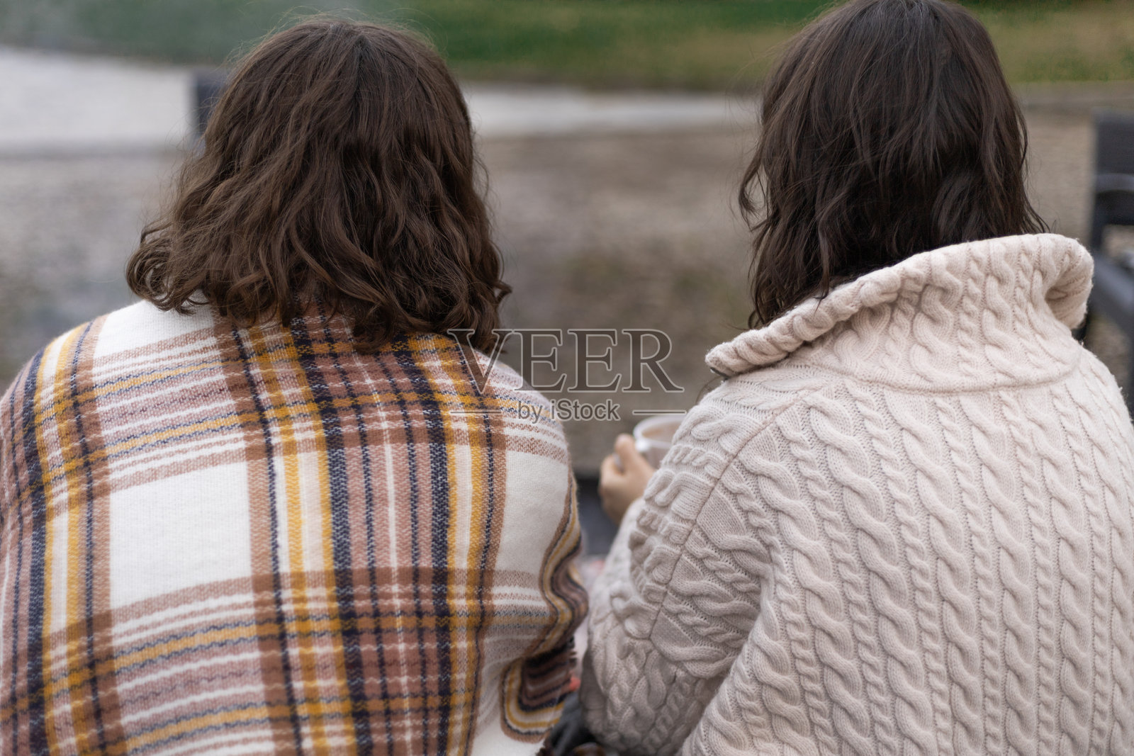 从后面看，两位穿着保暖的女士围坐在篝火旁照片摄影图片