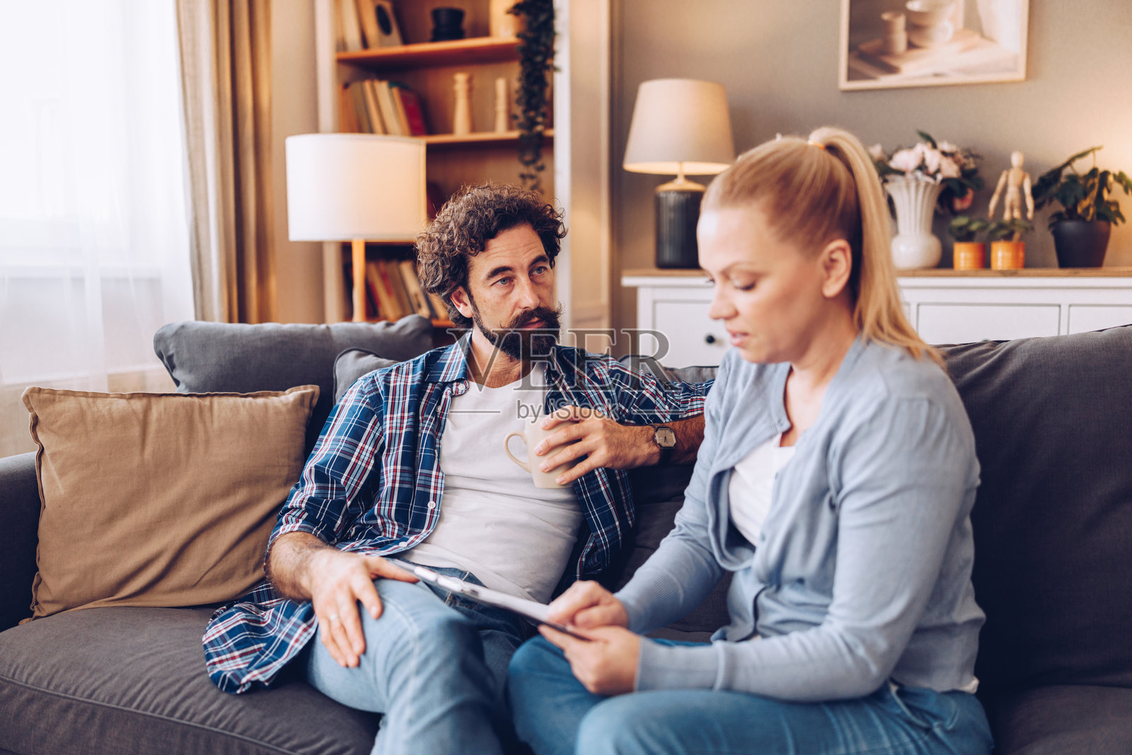 丈夫和妻子在家中沙发上管理家庭财务，看起来有些担忧。照片摄影图片