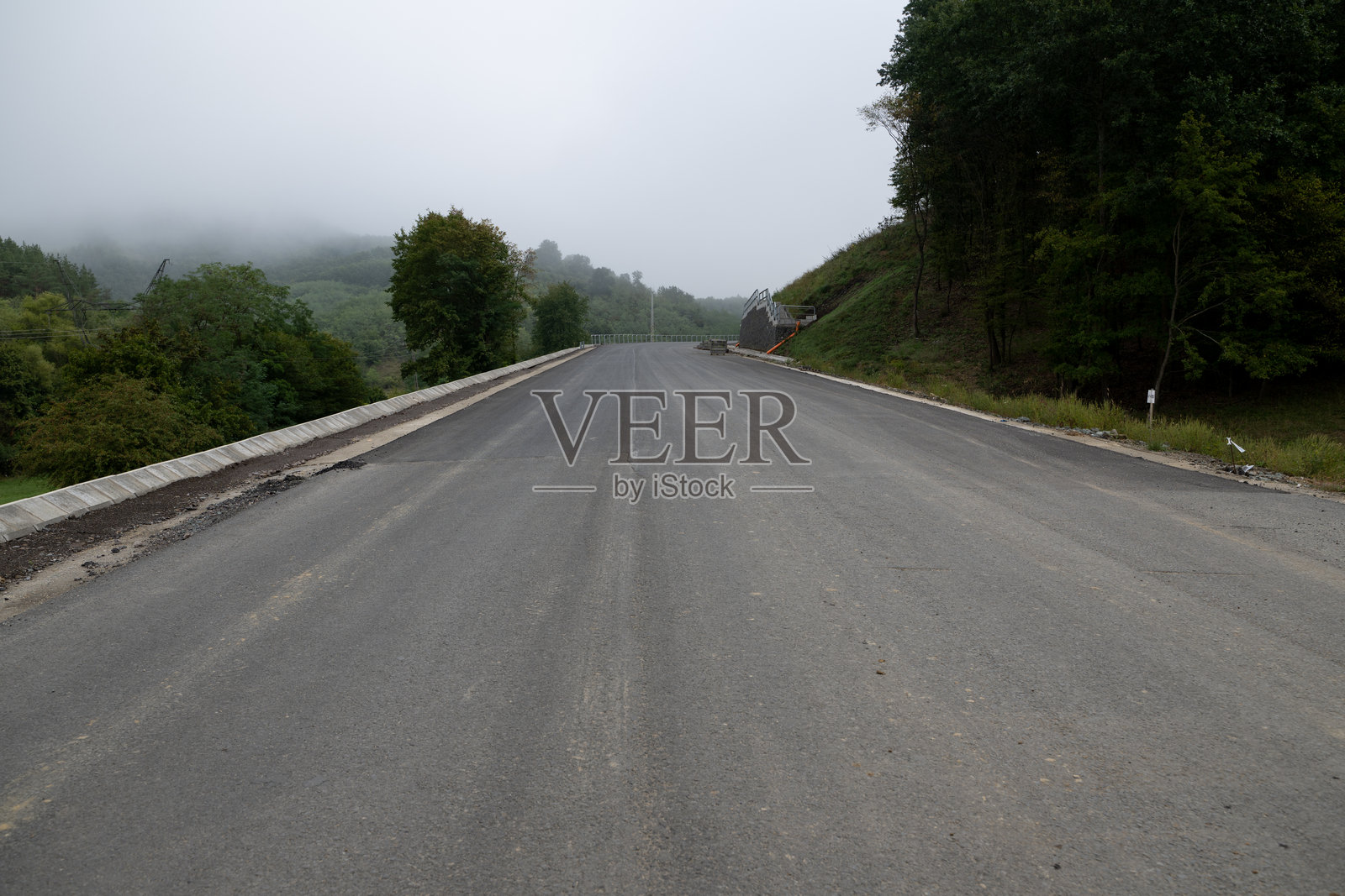 新铺设的乡村公路穿过薄雾笼罩的森林景观照片摄影图片