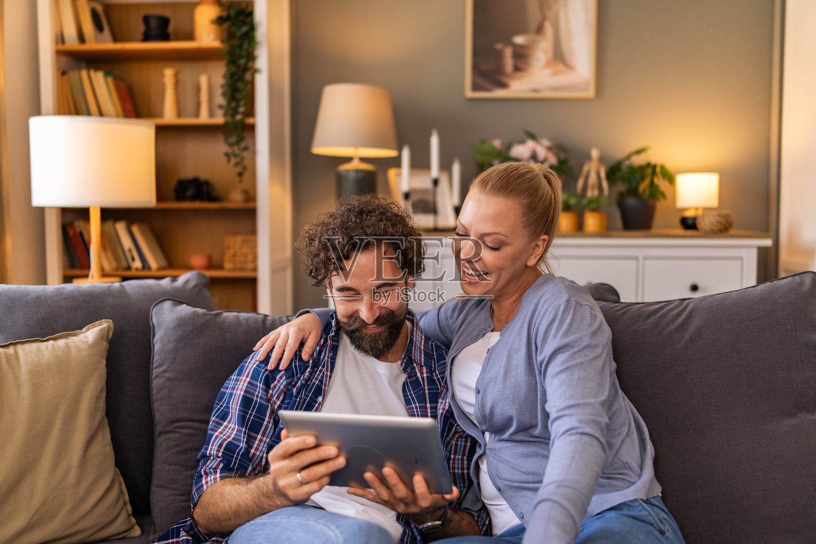 一对情侣在客厅的沙发上依偎着，通过平板电脑回顾着他们共同的美好回忆。照片摄影图片