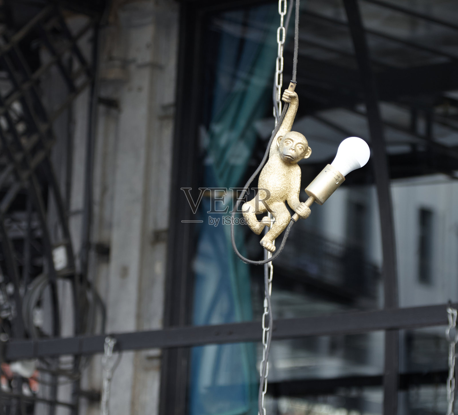 一盏金丝猴造型的灯具从建筑外部的链条上垂下，展现了独特的都市设计和俏皮的氛围照片摄影图片