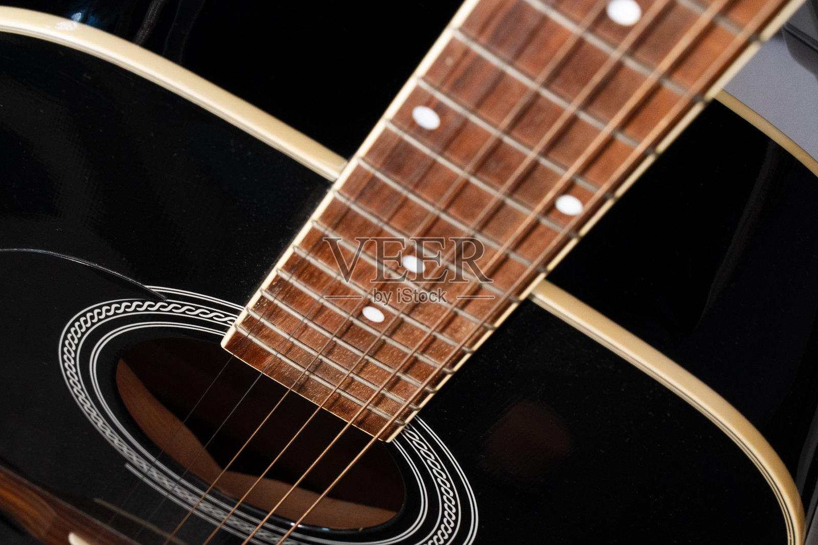 黑色的原声吉他，展示了指板、琴弦和音孔的细节照片摄影图片