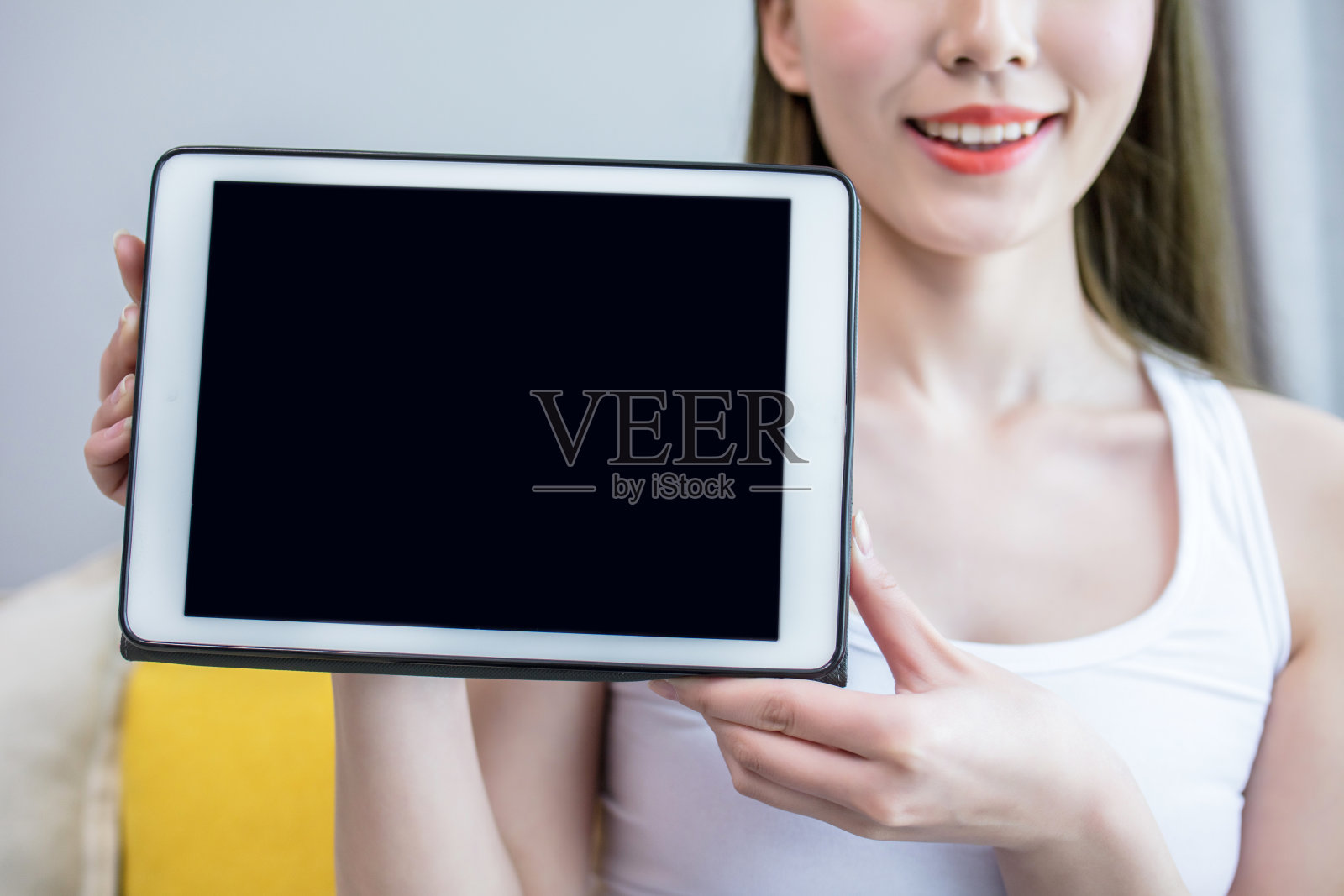 年轻女子在室内手持一块空白屏幕的平板电脑照片摄影图片
