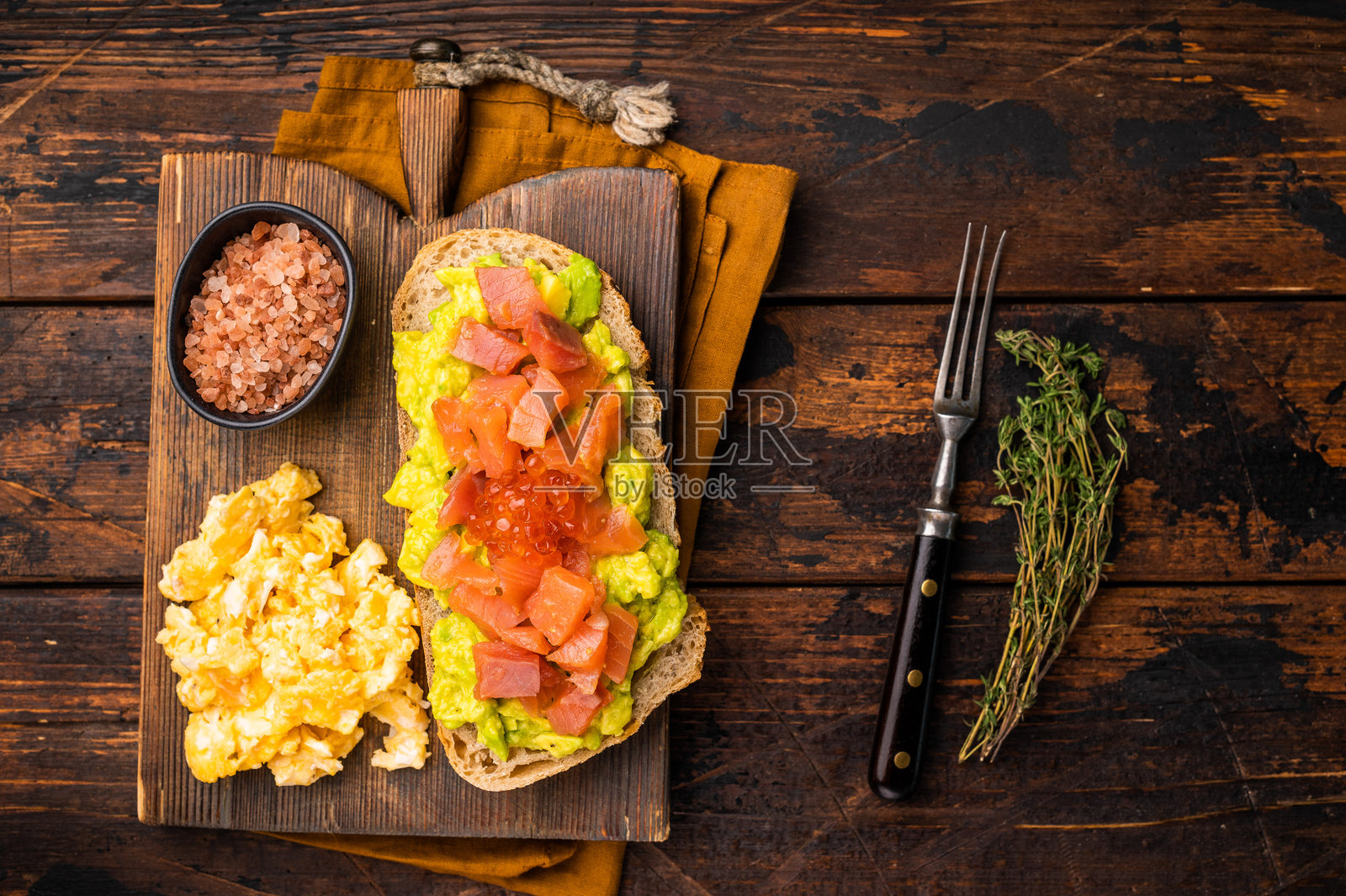 烟熏三文鱼、鳟鱼、牛油果和红鱼子酱三明治。木质背景。俯视图照片摄影图片