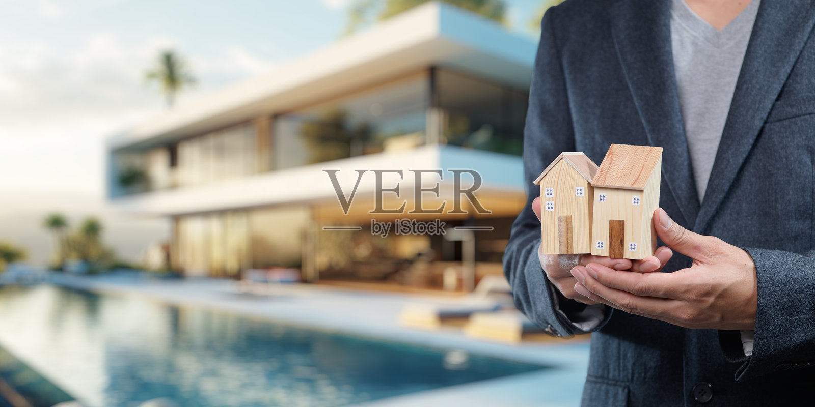 双手捧着模型房屋，前面是现代豪华住宅照片摄影图片