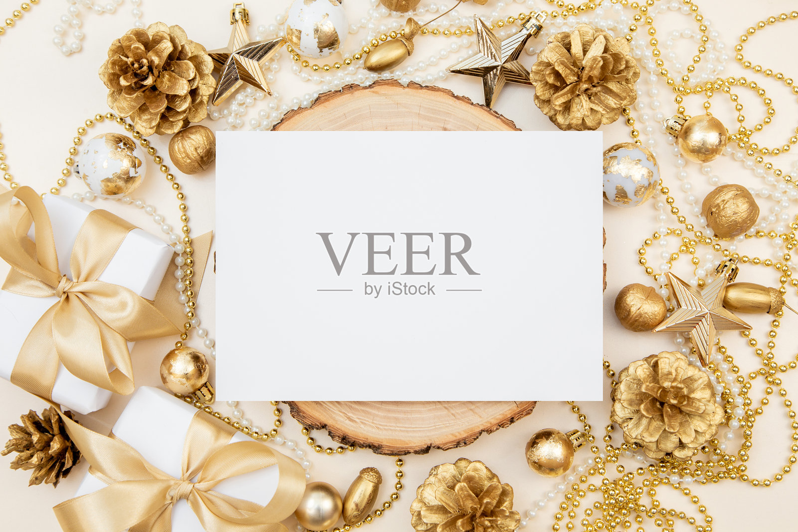 横放的空白纸张放在木片上，周围环绕着金色的圣诞和新年装饰品。俯视角度，留有空白区域，适合节日设计或邀请函。照片摄影图片