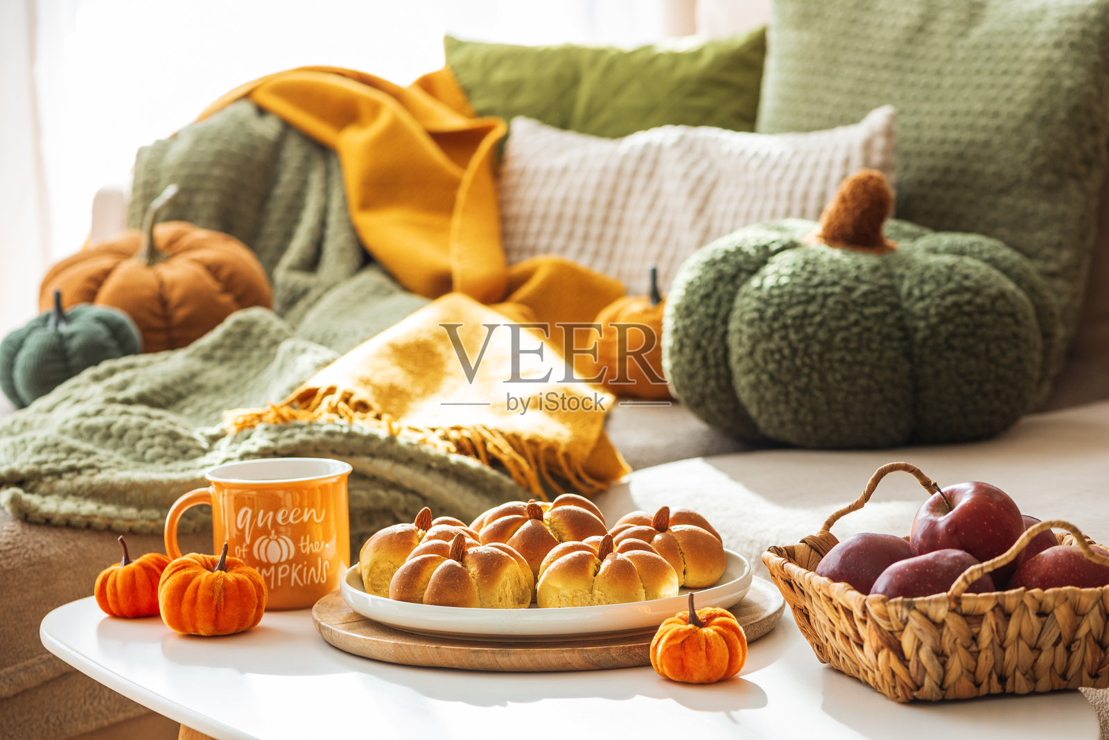 秋季餐桌布置，摆放着南瓜造型的肉桂面包、苹果、南瓜和温馨的装饰照片摄影图片