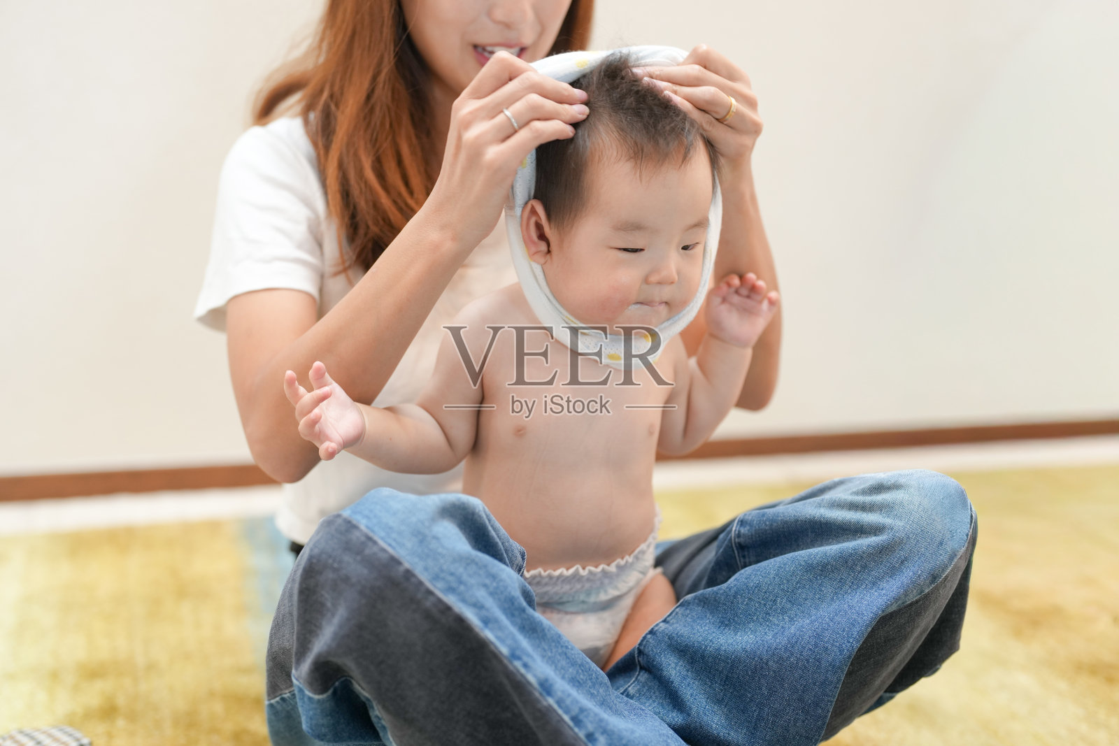 一位女子正托着婴儿的头部，并用一块布盖在上面照片摄影图片