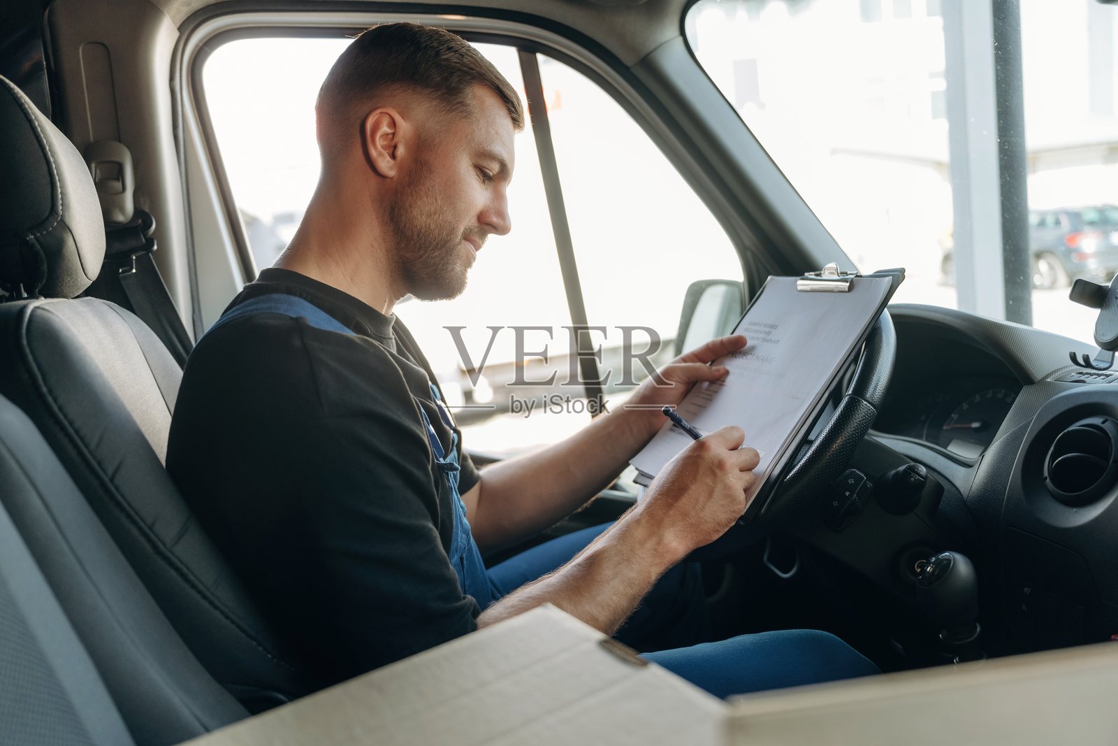 穿着制服的送货员在公交车内填写文件，在发票上书写。照片摄影图片
