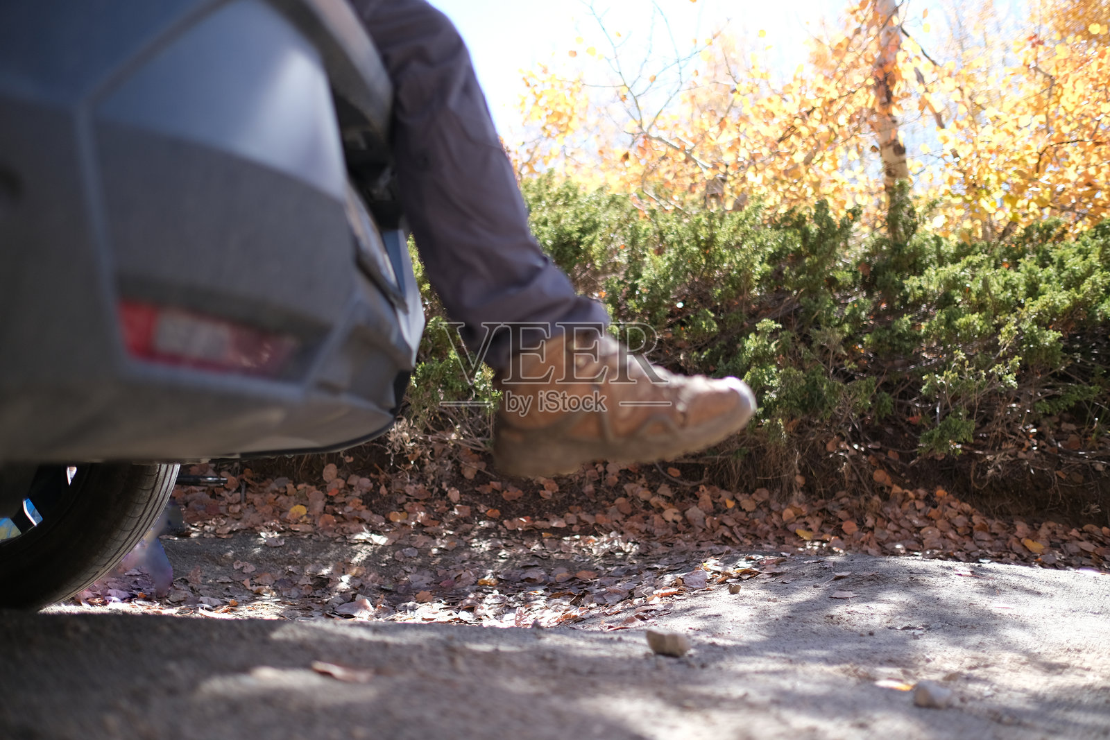 一位登山者坐在车上露营，双脚悬在车外。照片摄影图片