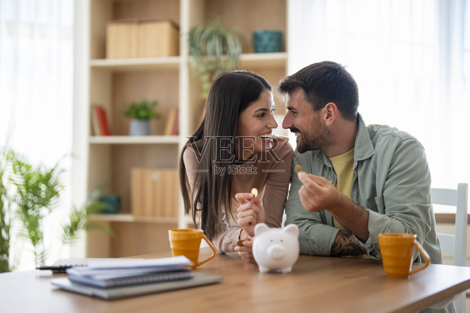 快乐的夫妇在家一起用存钱罐存钱照片摄影图片