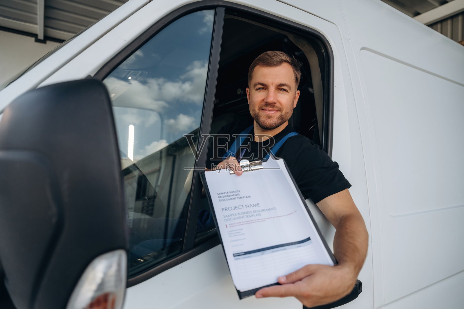 填写文件的快递员，一位快递服务公司的员工正坐在货车里照片摄影图片