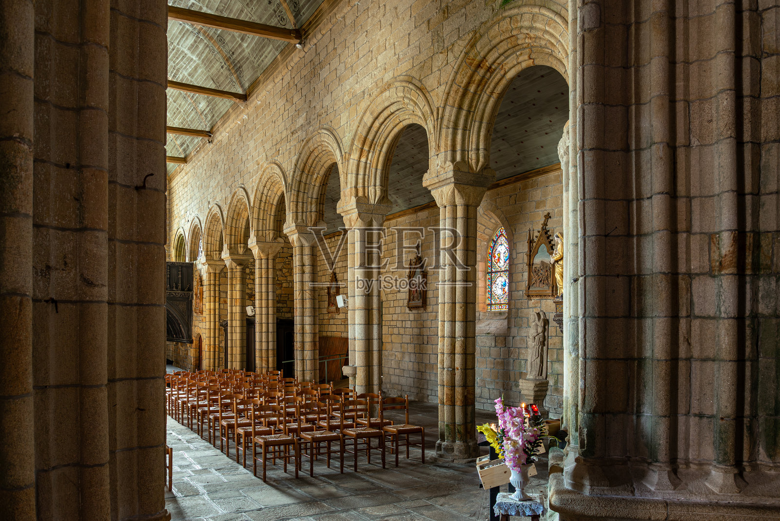 法国布列塔尼蓬克鲁瓦诺特丹德罗斯屈当历史教堂内的彩绘玻璃，带有祭坛、雕像和木制座椅照片摄影图片