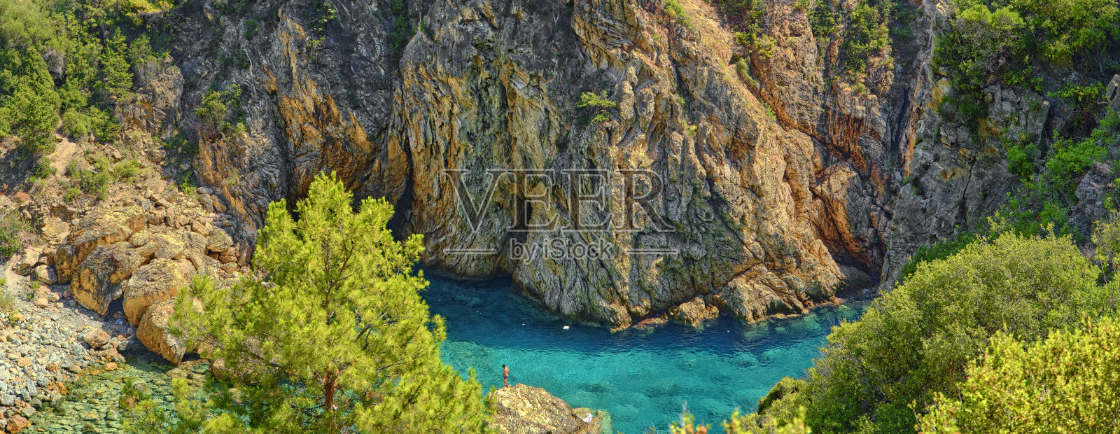 郁郁葱葱的绿植环绕着岩石峭壁和宁静的绿松石海湾的风景照片摄影图片