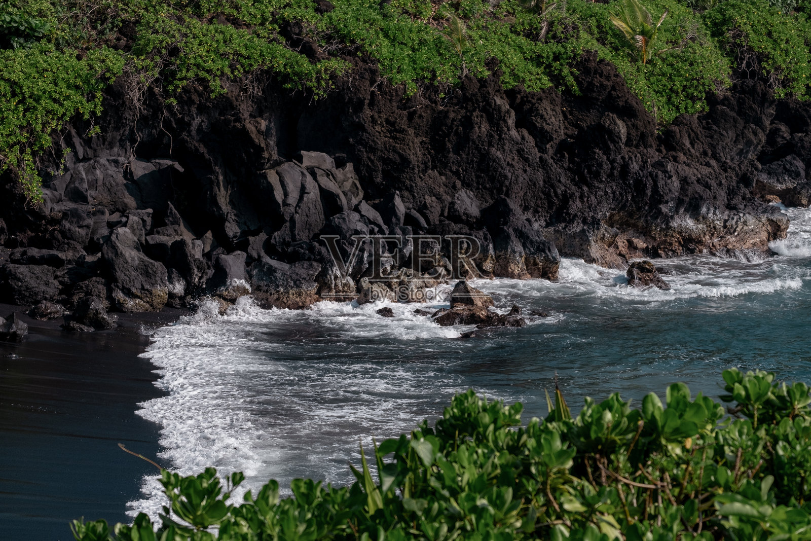 夏威夷毛伊岛哈纳之路沿途怀阿纳帕纳帕州立公园的戏剧性黑沙滩海浪，伴有火山岩和茂密的绿色植被照片摄影图片