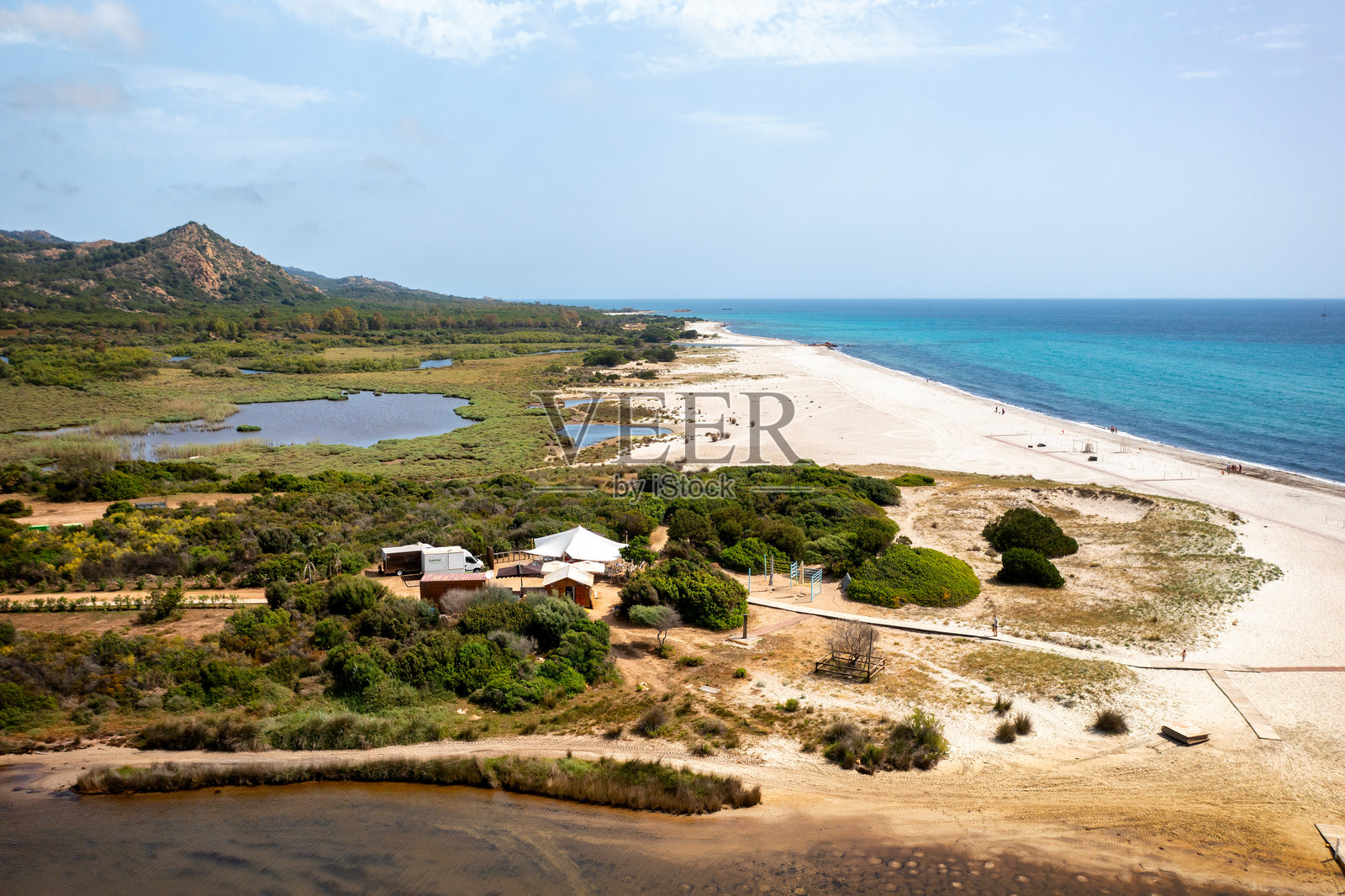 意大利撒丁岛贝尔基达海滩的鸟瞰图，拥有白色沙滩、绿松石般的海水和周围郁郁葱葱的植被照片摄影图片