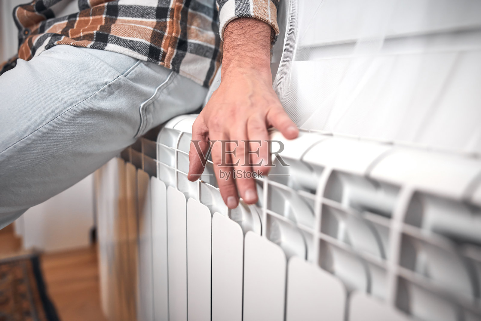 寒冷的冬日里，一个人在取暖，能源和天然气危机，寒冷的房间，供暖问题。照片摄影图片