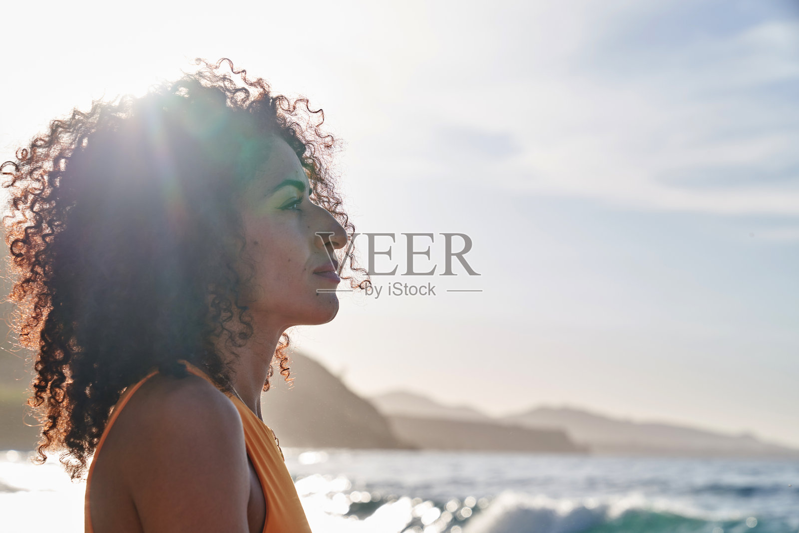 卷发女子眺望海边日落照片摄影图片