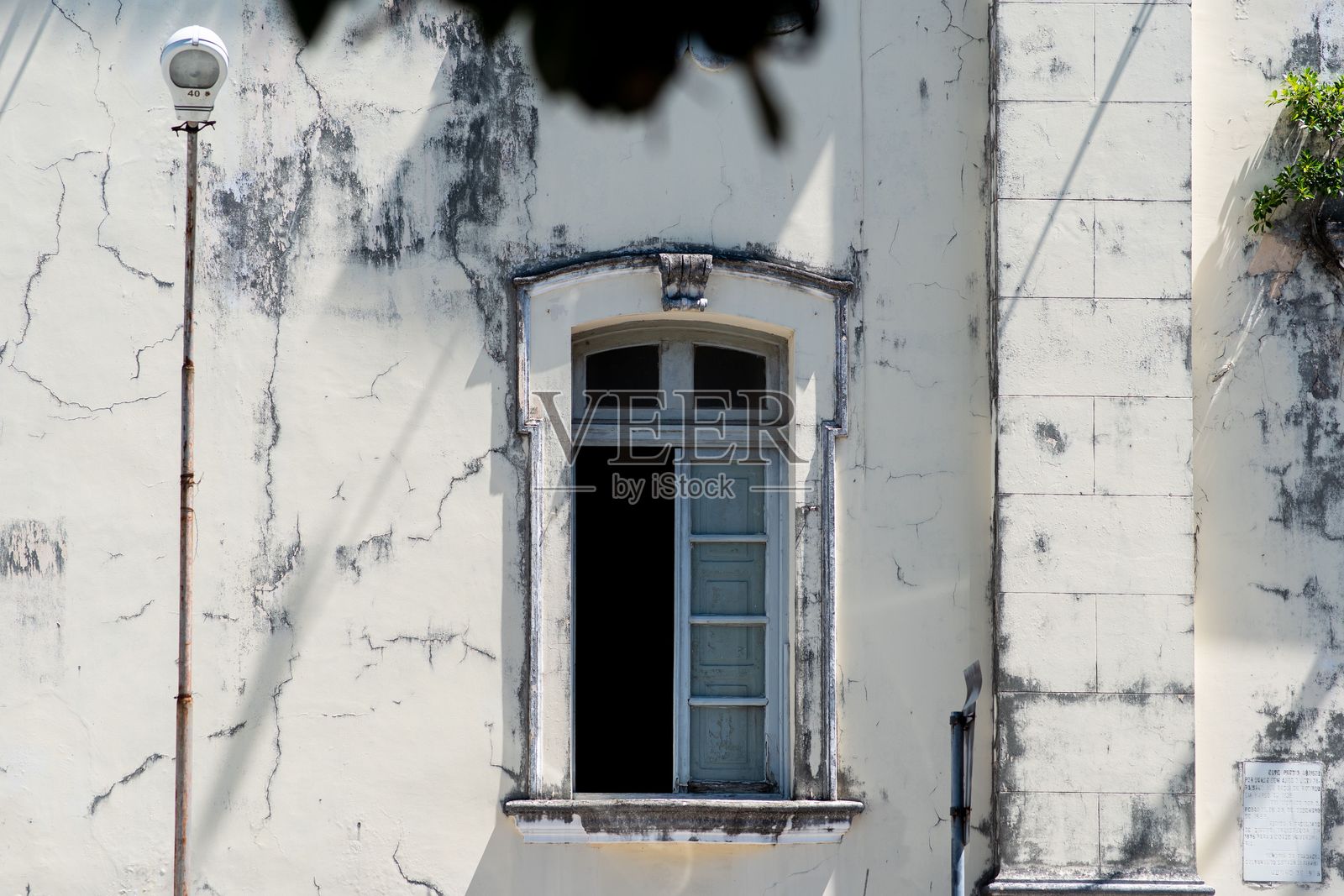 饱经风霜的奶油色墙壁，蓝色窗户半开，露出剥落的油漆和岁月的痕迹照片摄影图片