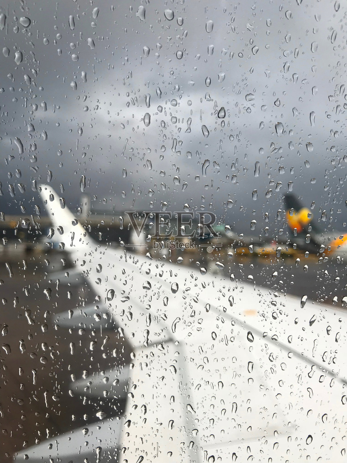 暴风雨天气下，机场飞机窗户上的雨滴照片摄影图片