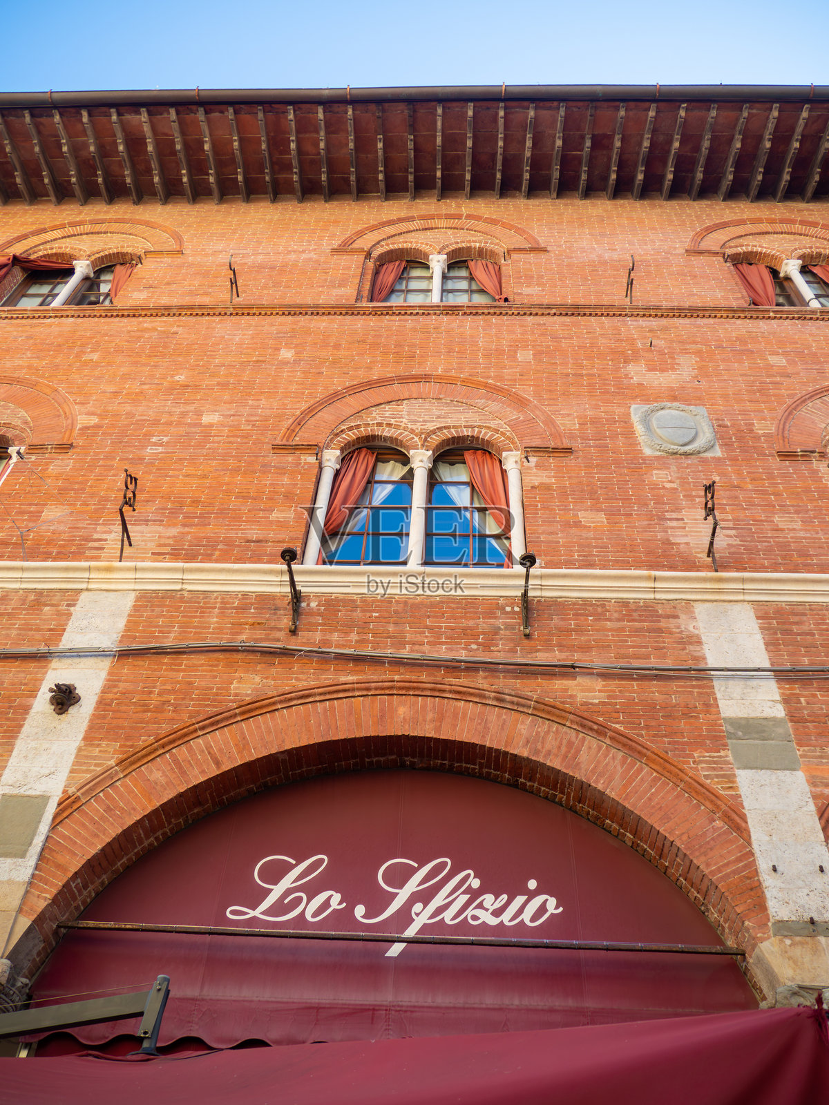 意大利比萨的老砖砌建筑外观，展示了历史建筑、多个拱形窗户以及“Lo Sfizio”标志照片摄影图片