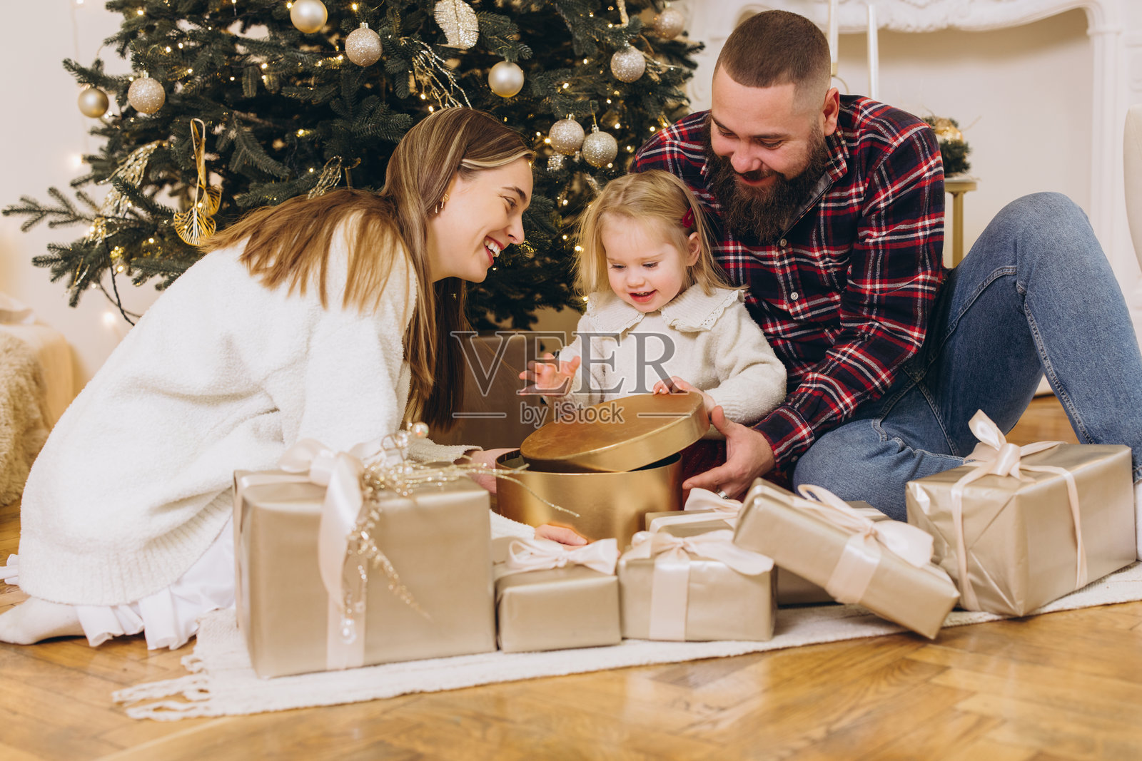 快乐的一家人在装饰好的圣诞树旁拆礼物照片摄影图片