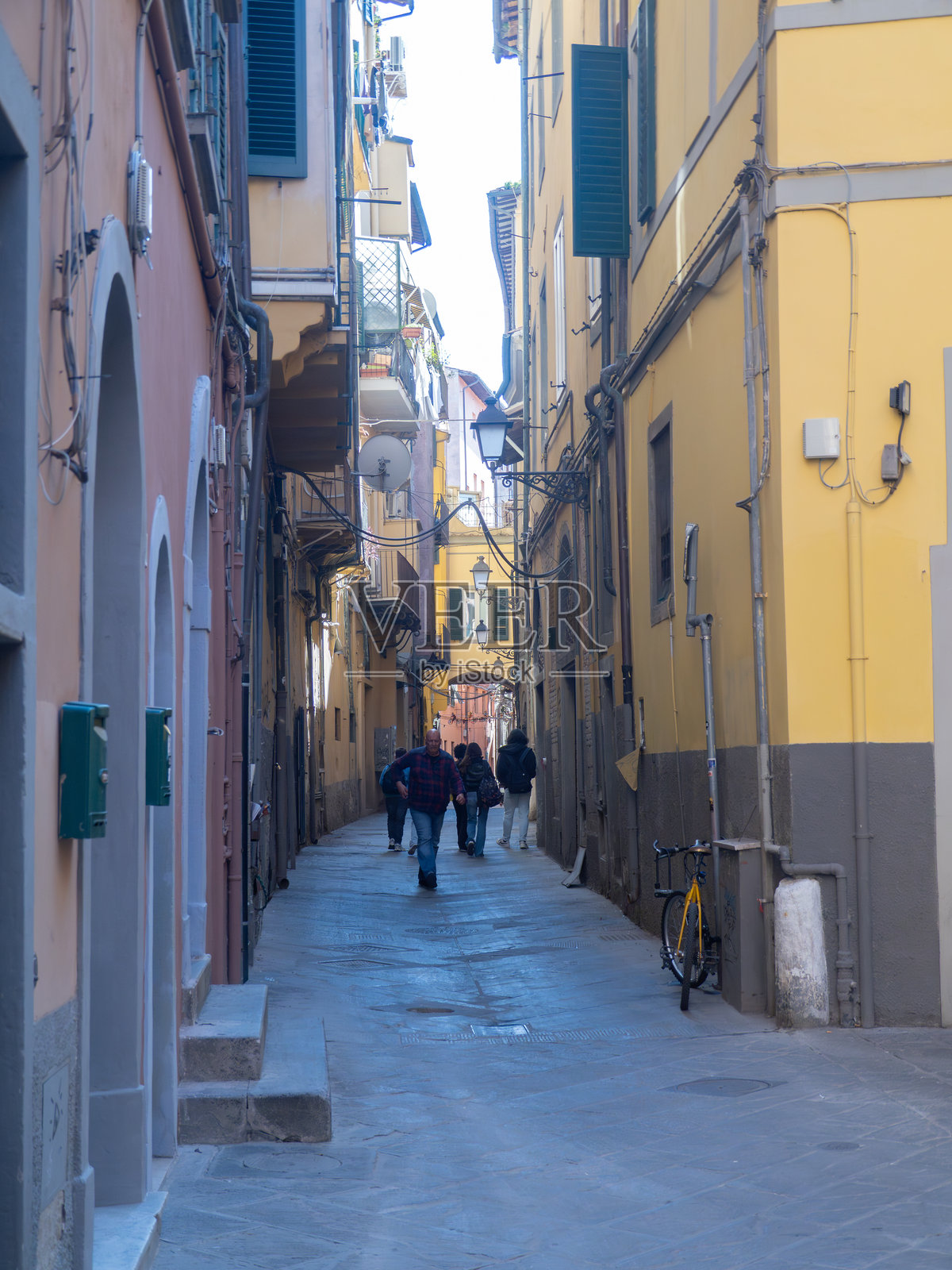 人们走在意大利托斯卡纳比萨历史区狭窄的鹅卵石小巷中照片摄影图片