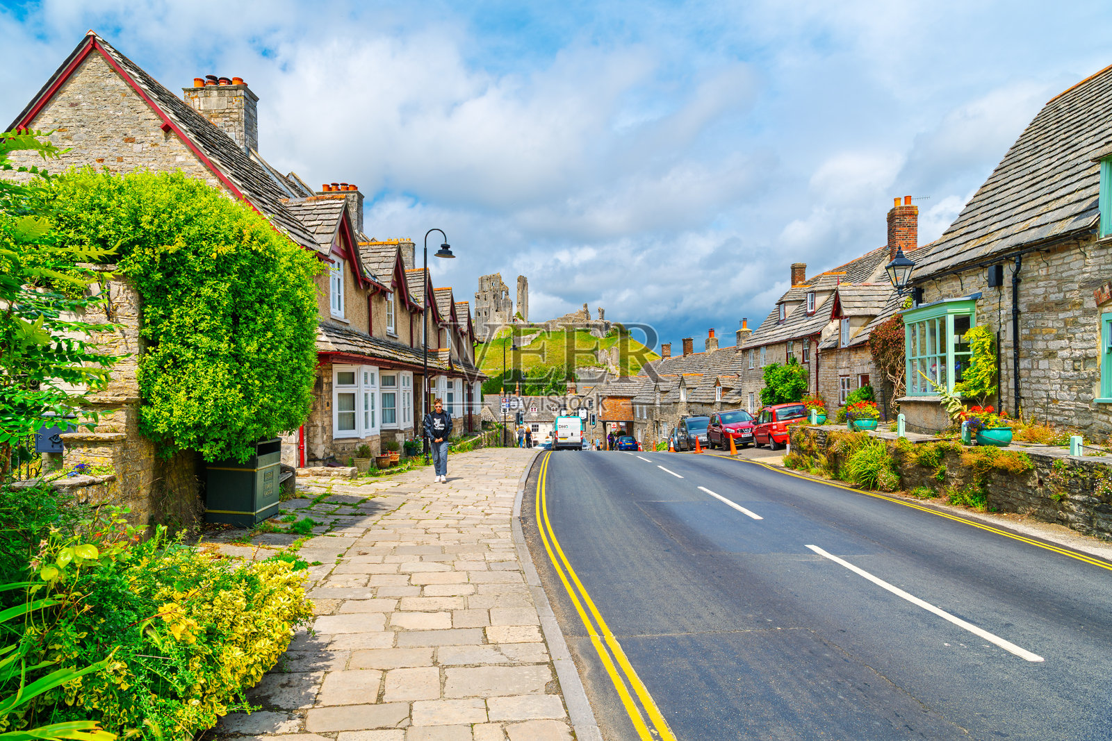 英格兰科夫城堡，一座风景如画的石头建筑街道，有商店和住宅，远处是中世纪城堡。照片摄影图片