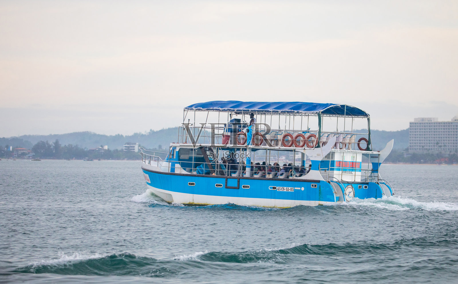 载有乘客的蓝色观光船在海浪上巡游照片摄影图片