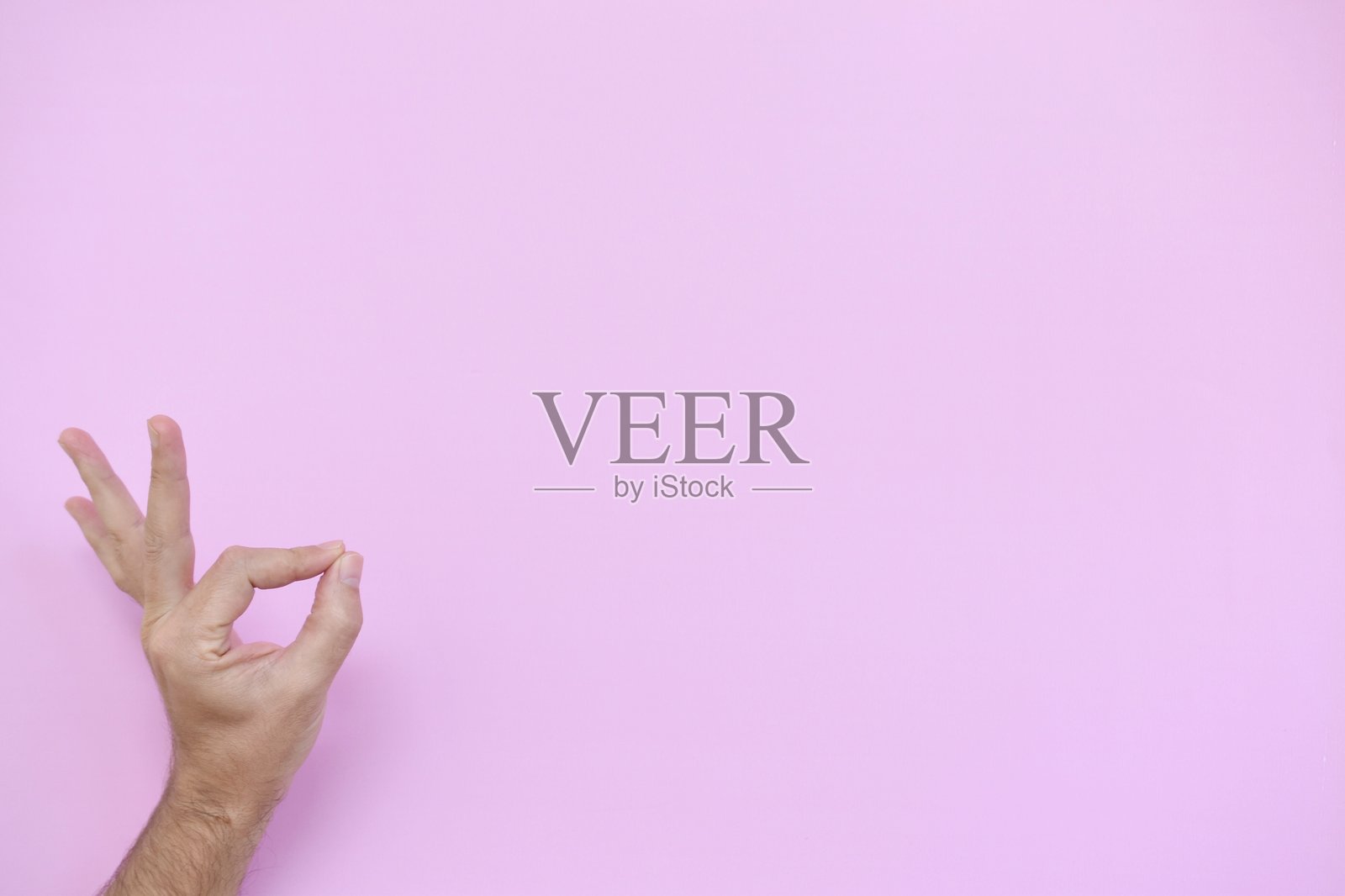 裁剪的手在粉色背景上做出OK手势照片摄影图片