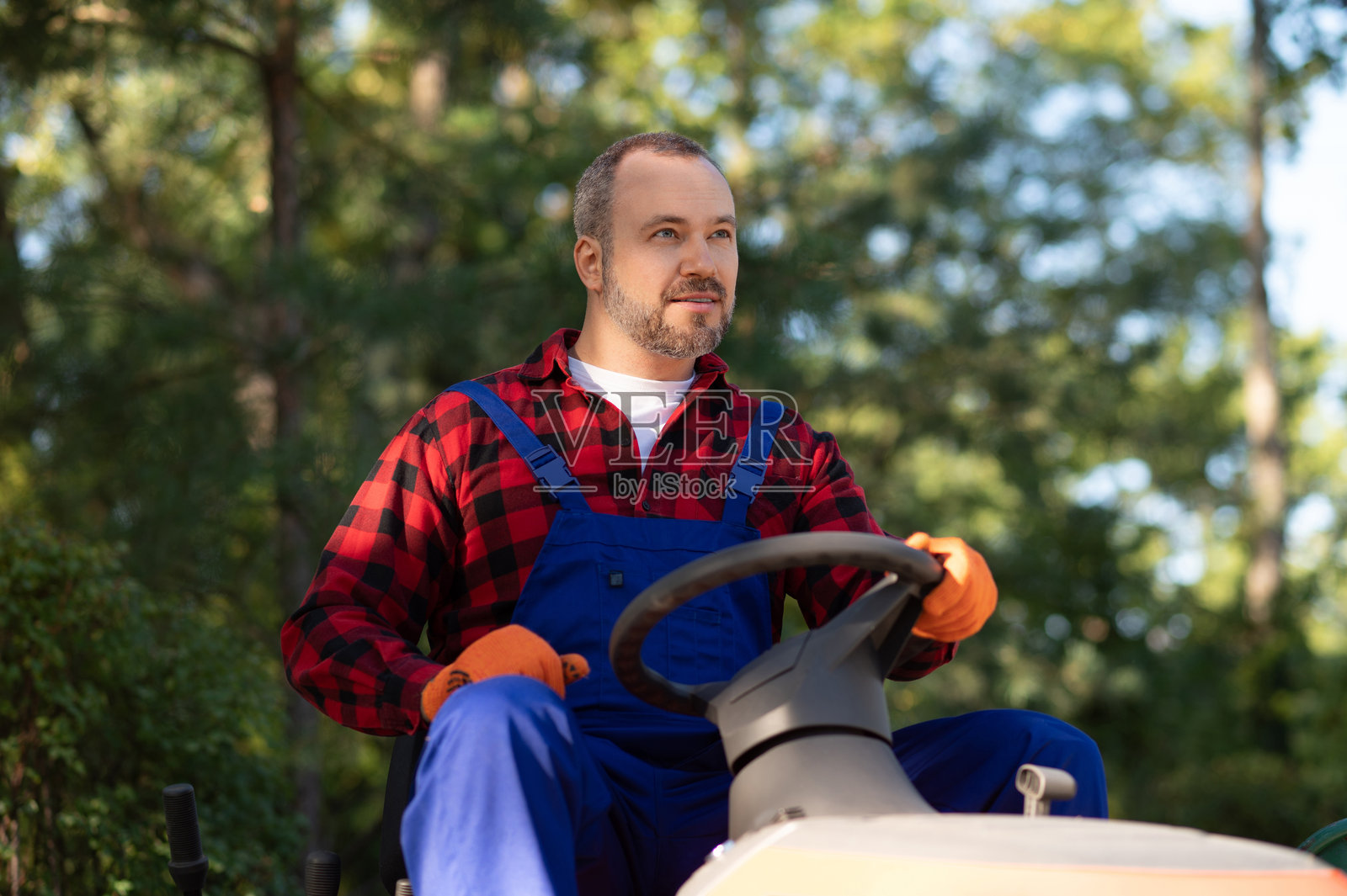 园丁坐在小型园艺车辆的驾驶座上照片摄影图片