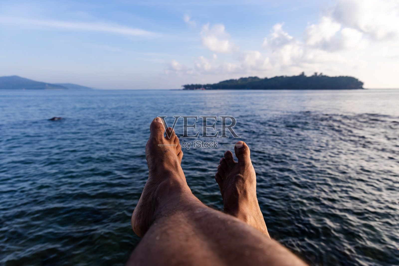 男人的赤脚，享受着平静蓝色大海和海平线的景色照片摄影图片