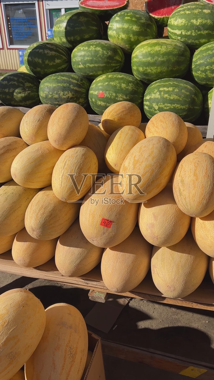 农贸市场摊位上，新鲜的瓜和西瓜摆放在木托盘上照片摄影图片