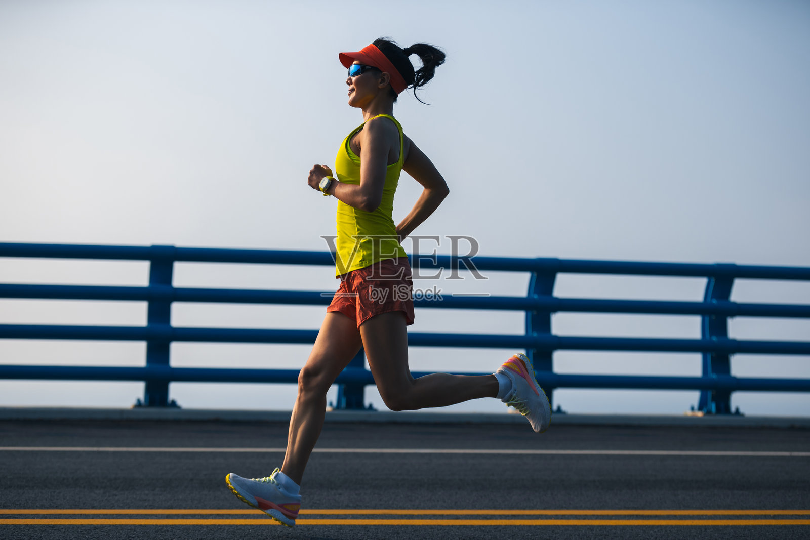 健身的亚洲女性跑者在海边桥上跑步照片摄影图片