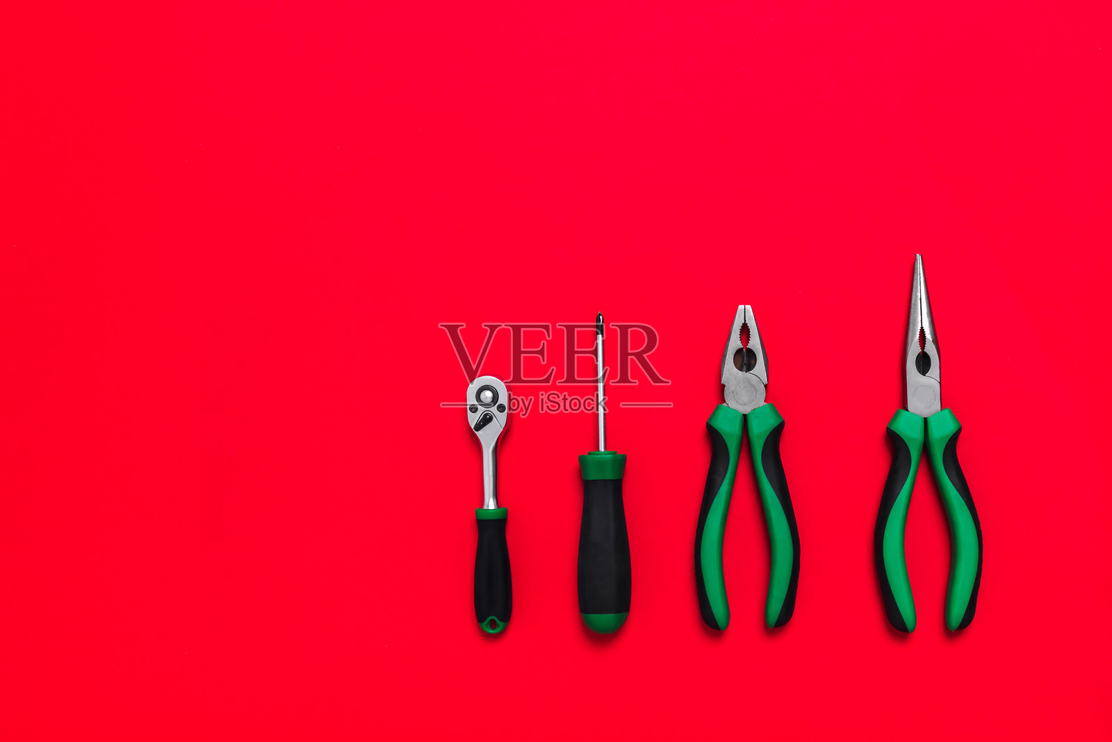 高品质绿色建筑钳子和螺丝刀工具，用于在红色背景上修理汽车或房屋。DIY工具。带有复制空间的建筑商店广告横幅。名片照片摄影图片