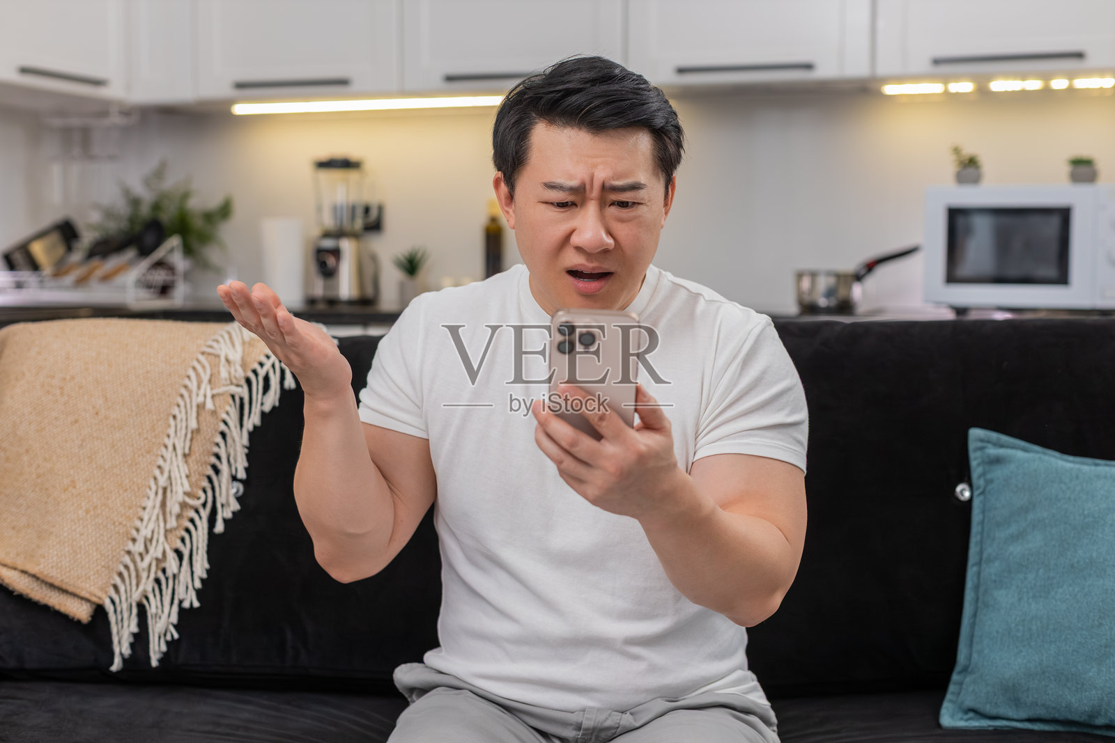 亚洲男子收到手机上的不良警报，皱着眉头，问为什么，摇头拒绝，展示停止标志，删除了邮件照片摄影图片